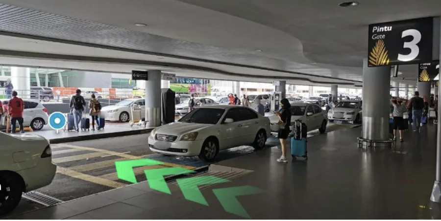 Arrivals hall exit at Gate 3 of Penang International Airport, with arrows pointing left along the kerbside.